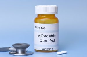 Affordable Care Act prescription bottle on blue with sethescope and pills.